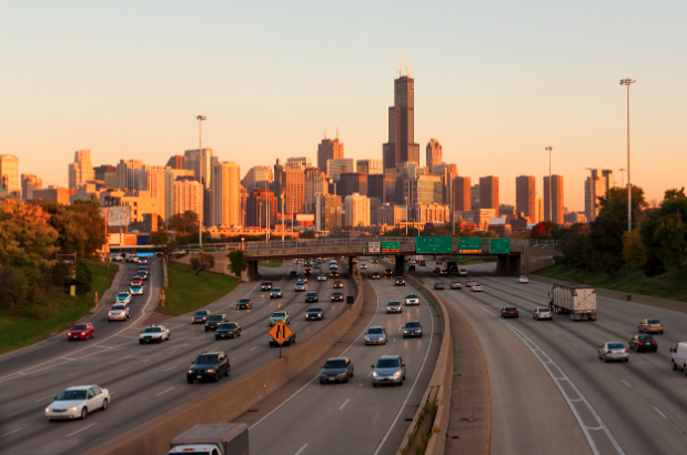 Car-filled highway in Chicago at sunset with the skyline in the background.